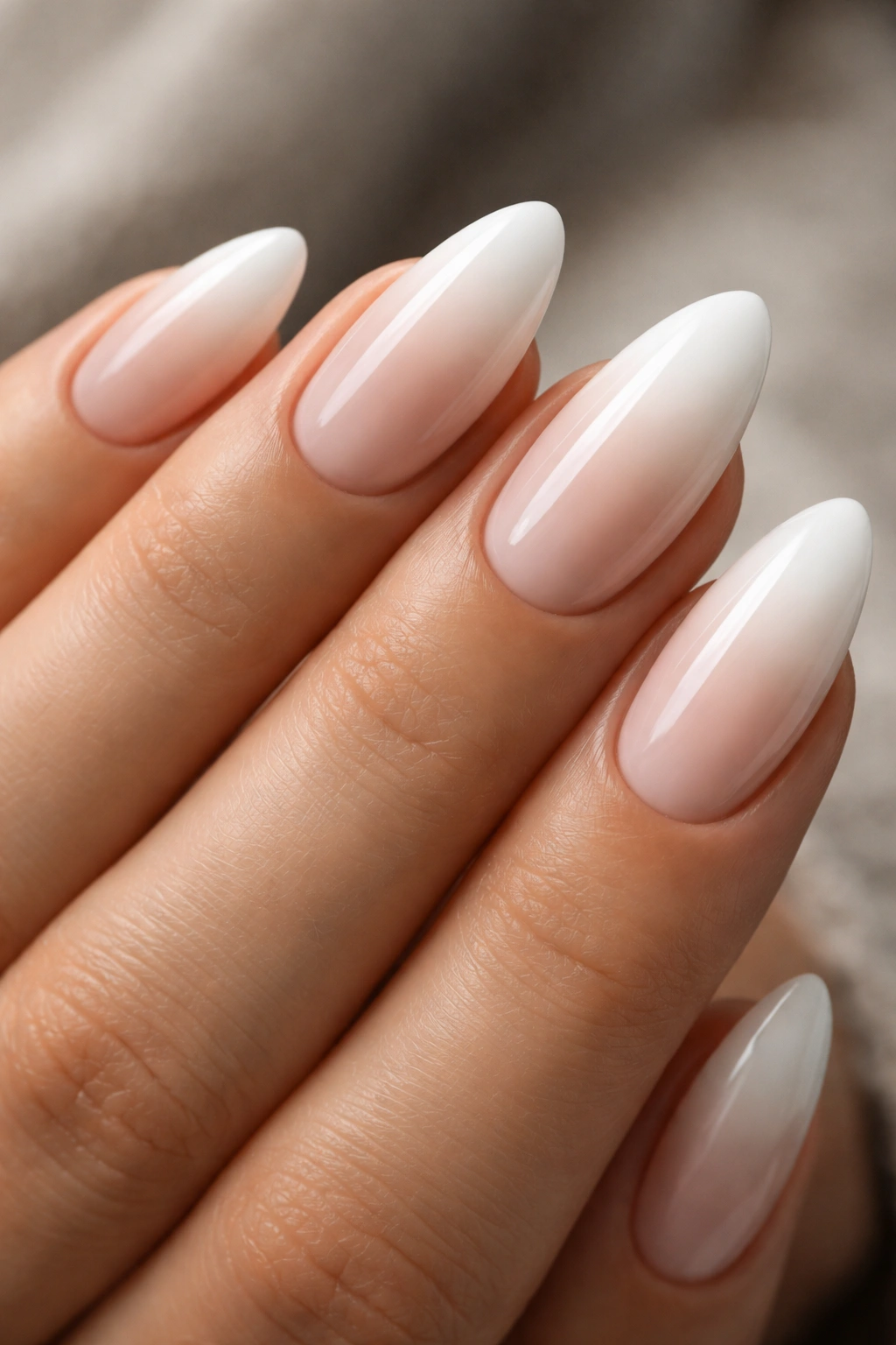 Close-up of white almond nails with nude ombre gradient
