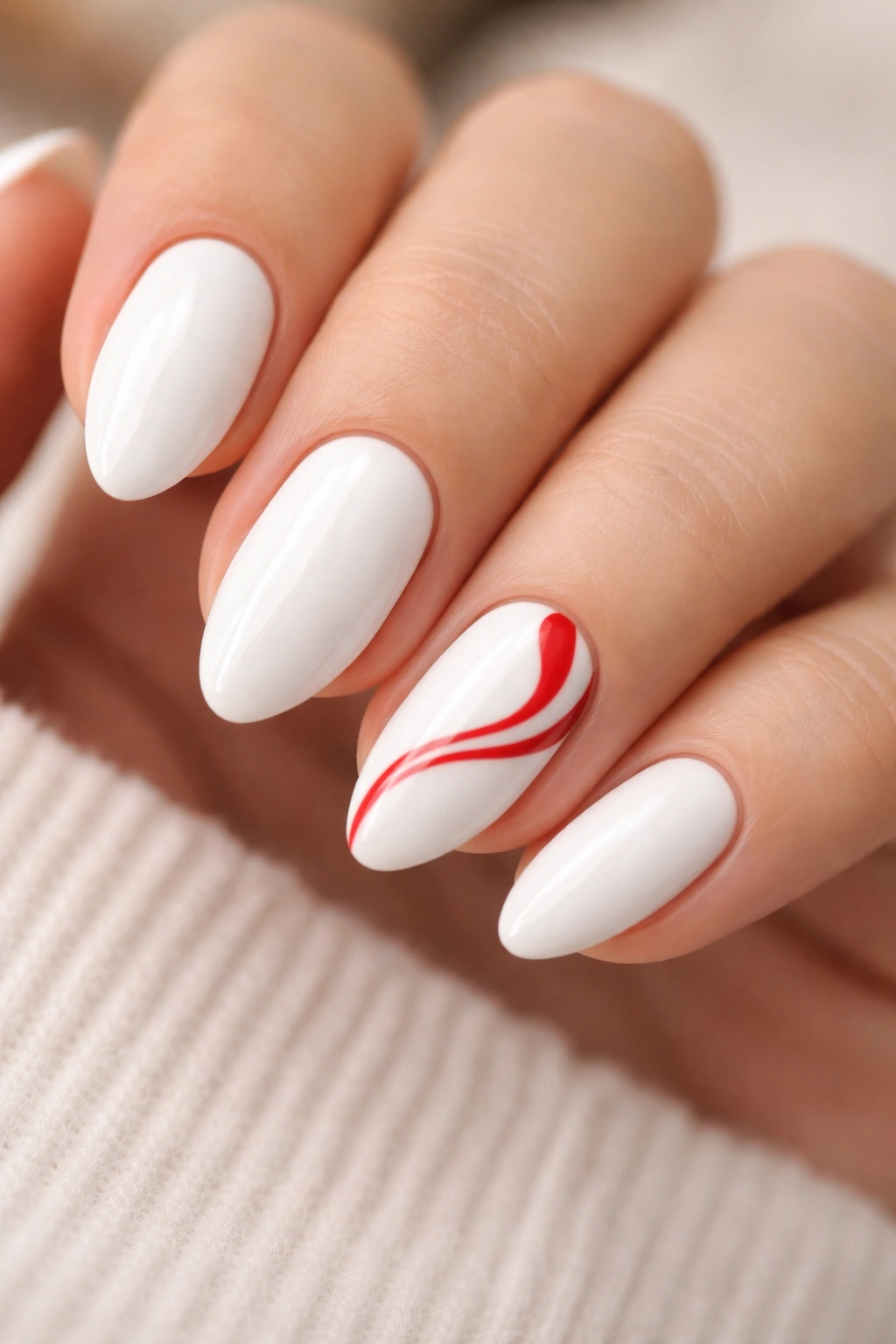 Close-up of white almond nails with red swirl accents