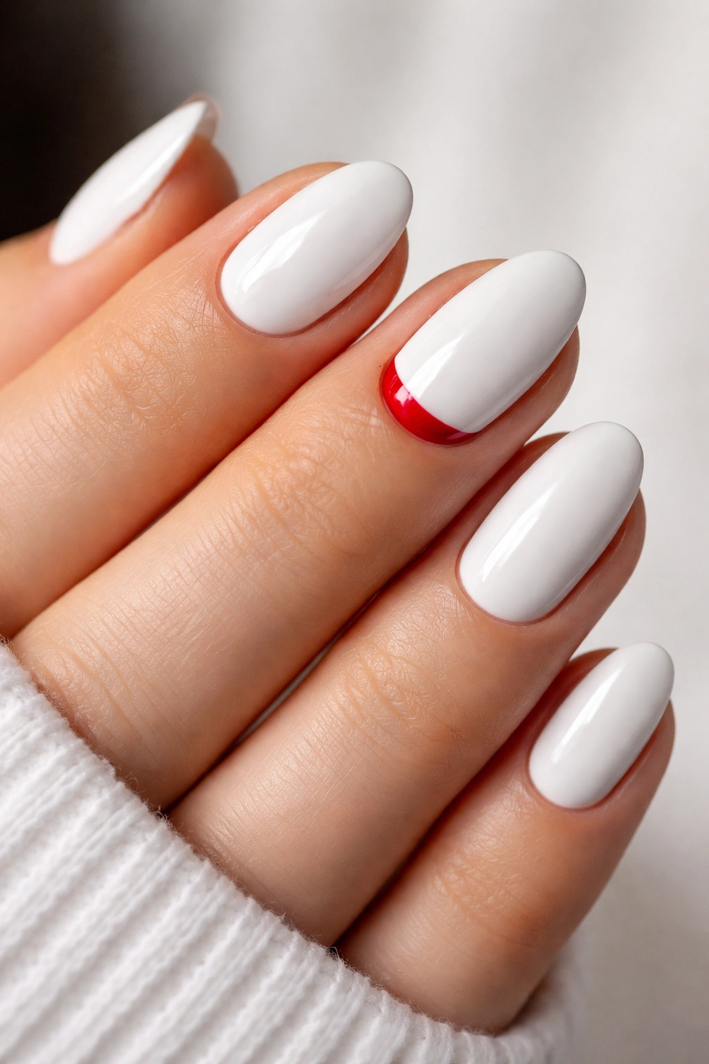 Close-up of short white almond nails with a red cuticle moon accent