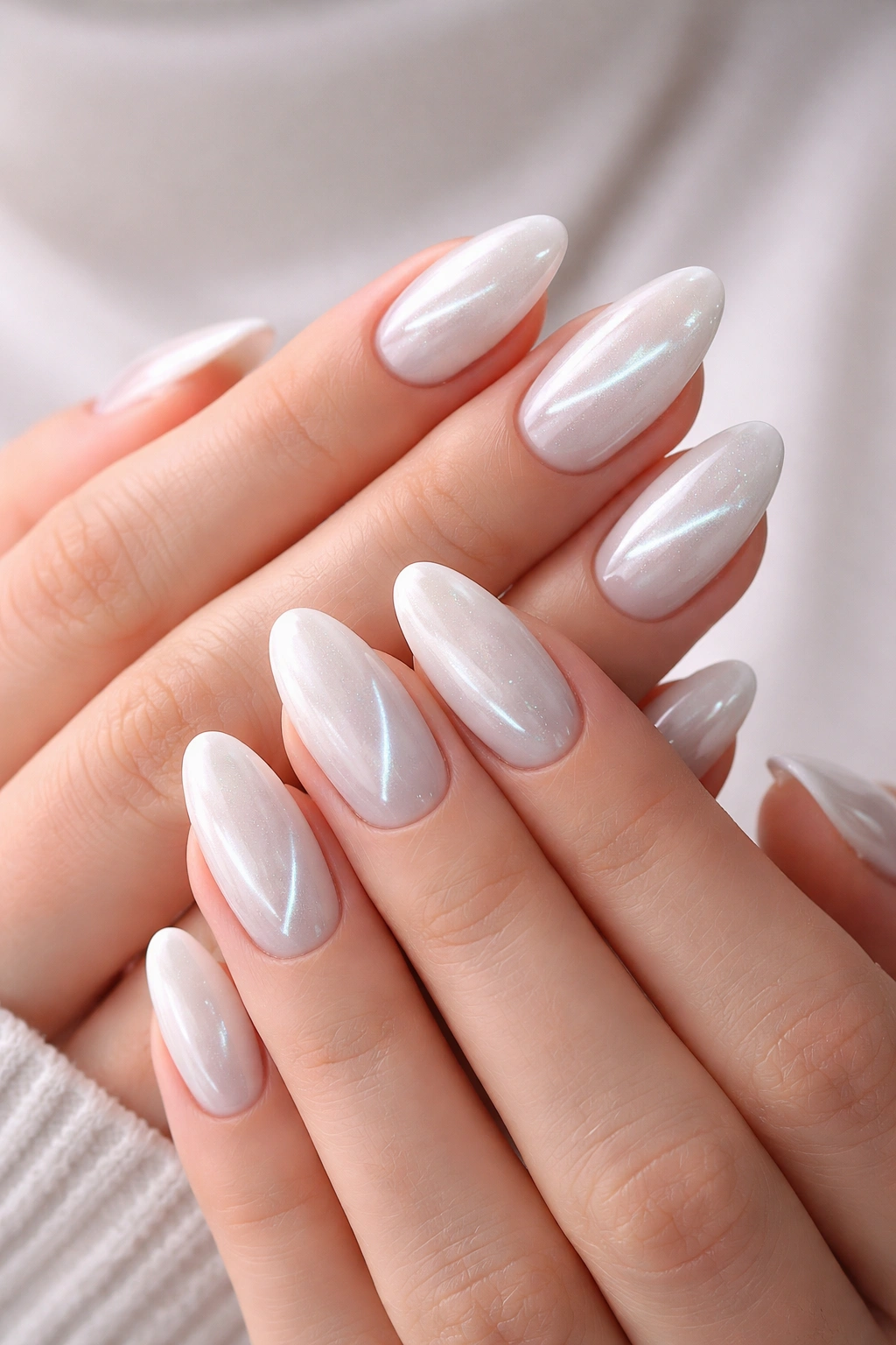 Close-up of hands with white cat eye manicure showing magnetic shimmer