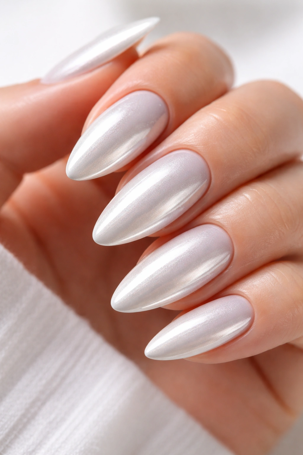 Close-up of white chrome almond nails with reflective metallic finish