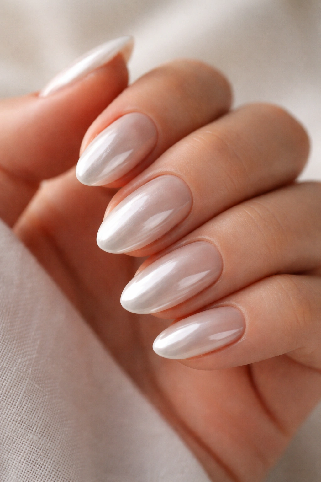 Close-up of short almond nails with nude base and white chrome overlay