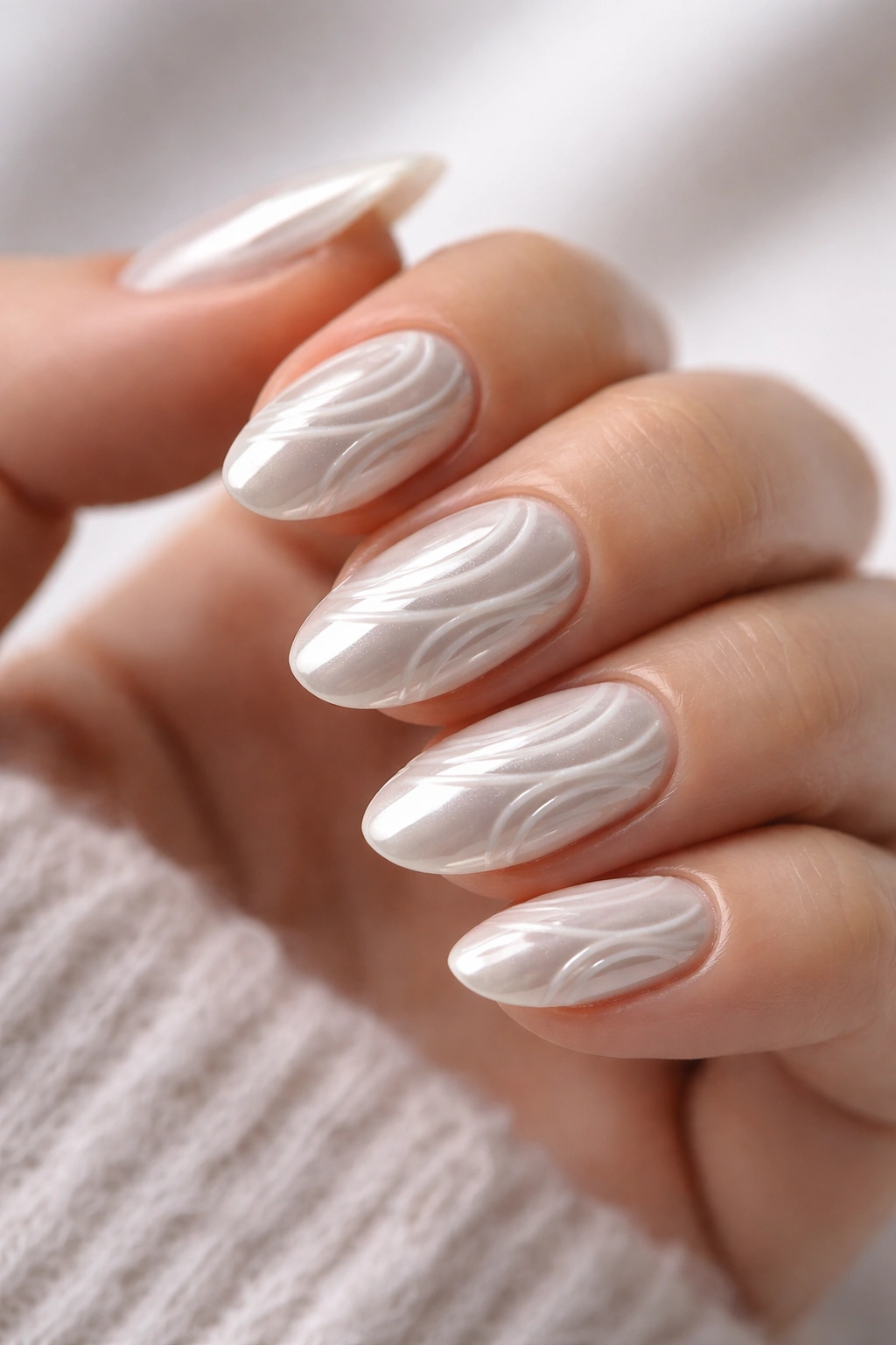 Close-up of short almond nails with white 3D swirls and chrome finish
