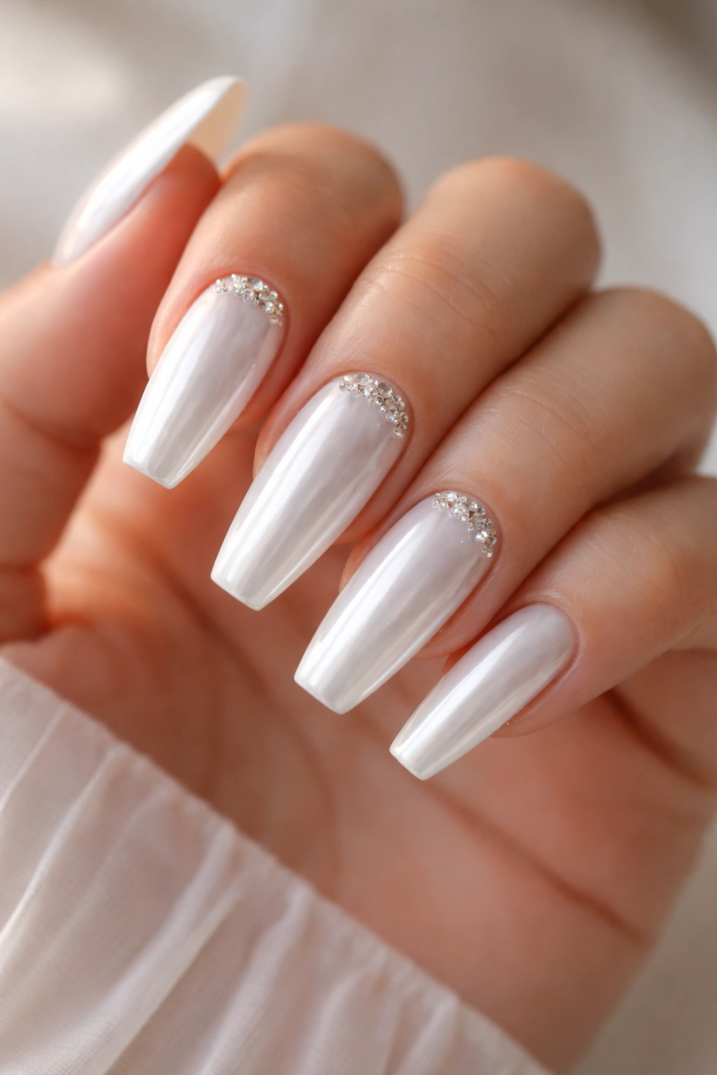 White chrome nails with tiny crystal clusters near the cuticle