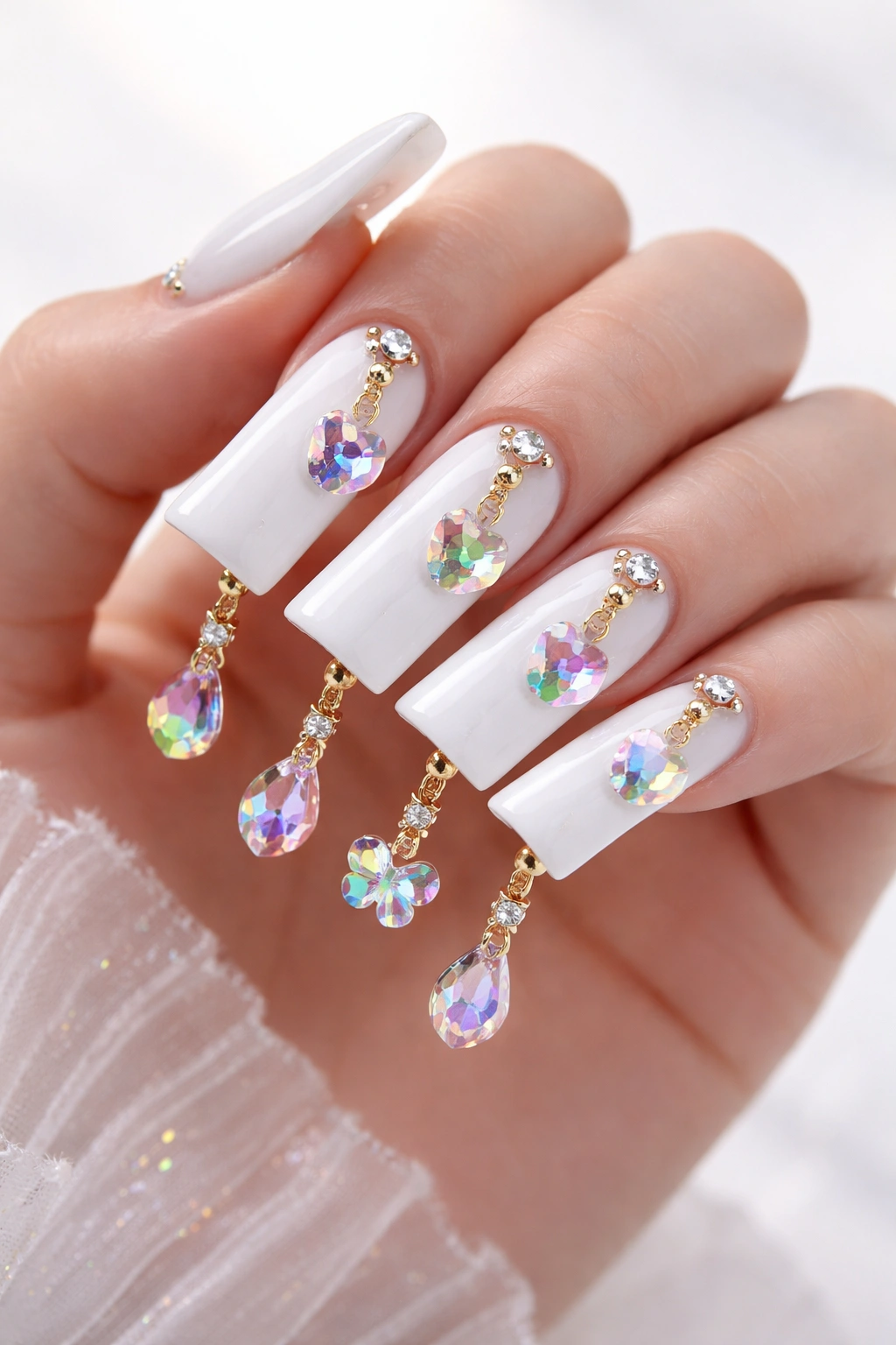 Close-up of glossy white duck nails with rainbow crystal charms