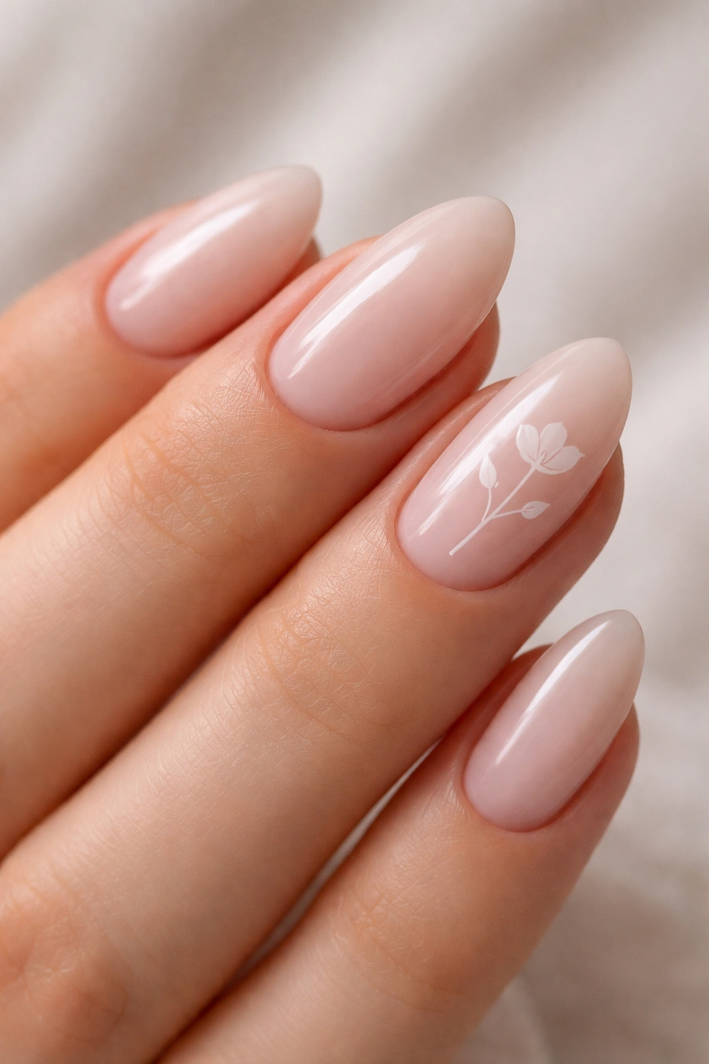 Close-up of white floral line art on a sheer pink base on short almond nails