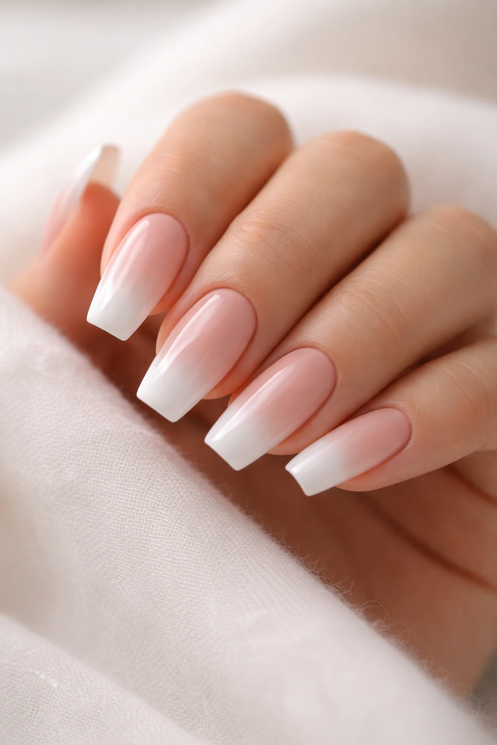 Close-up of medium coffin nails with nude base and soft white gradient tips