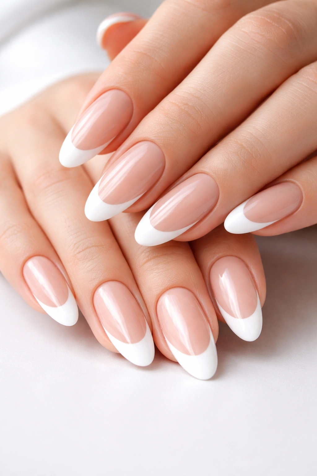 Close-up of long oval nails with crisp white French tips over a nude base