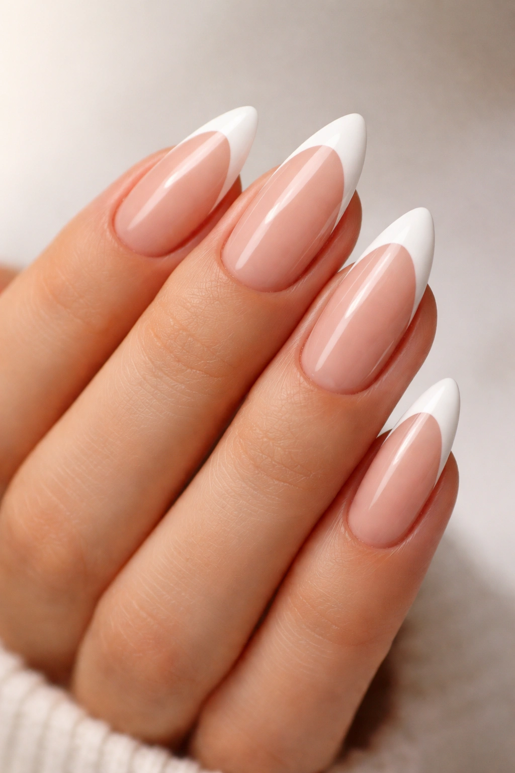Close-up of white French tip almond nails showing curved white tips