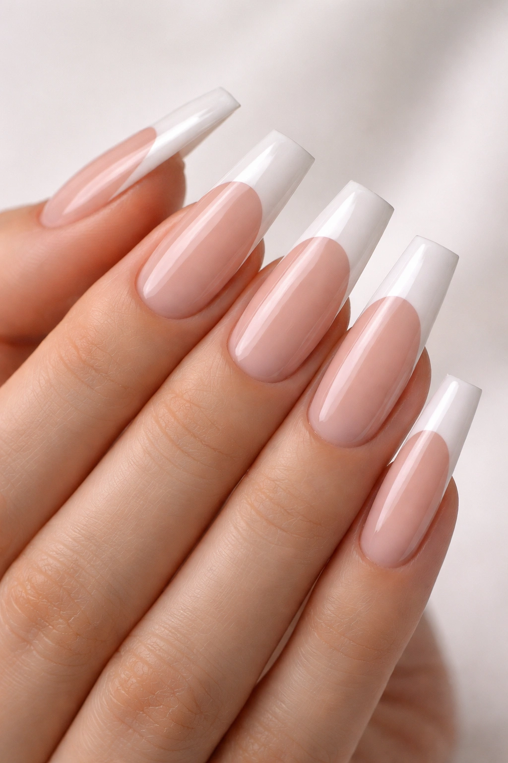 Long acrylic nails with white French tips on nude base close-up