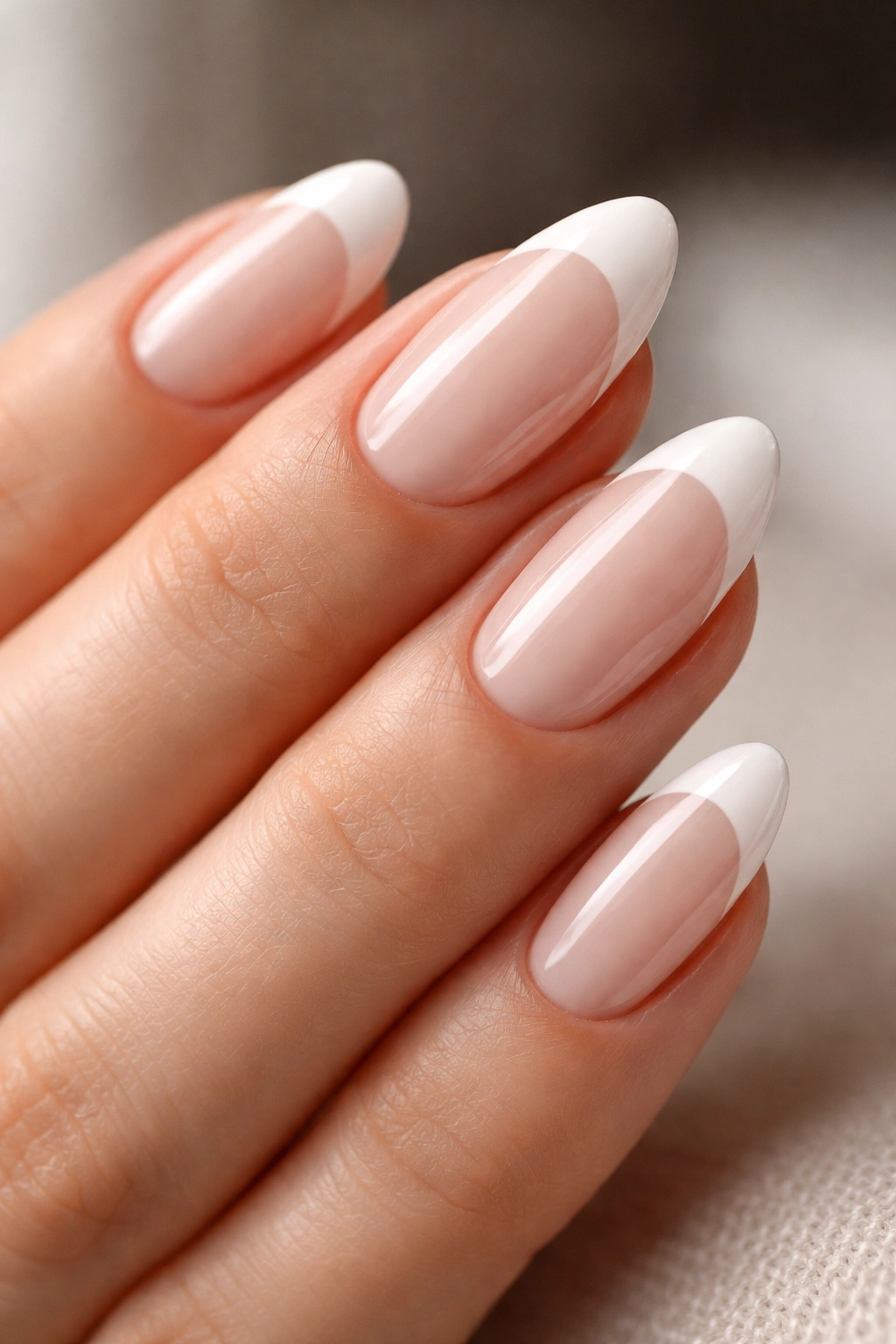 Close-up of almond nails with white French tips and glossy finish