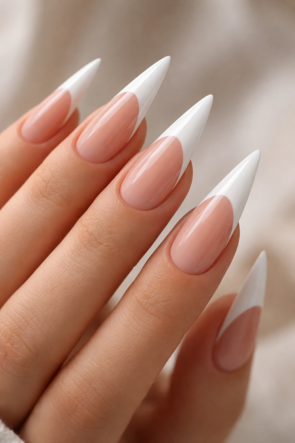 White stiletto nails with elongated white French tips on nude base