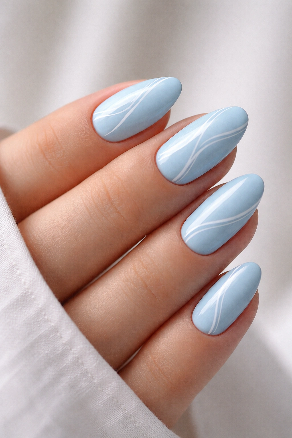 Close-up of baby blue nails with minimal white line art on short almond nails