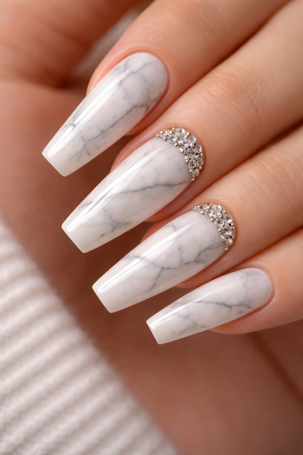 Close-up of white marble nails with a tiny cuticle crystal accent on one or two nails
