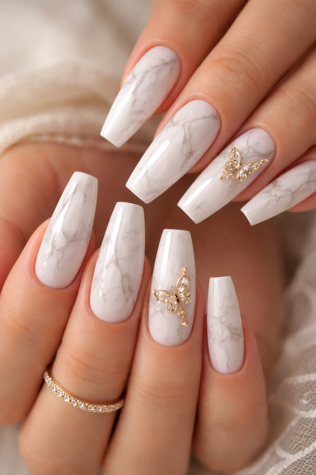 White marble nails with gold butterfly accents on a few nails
