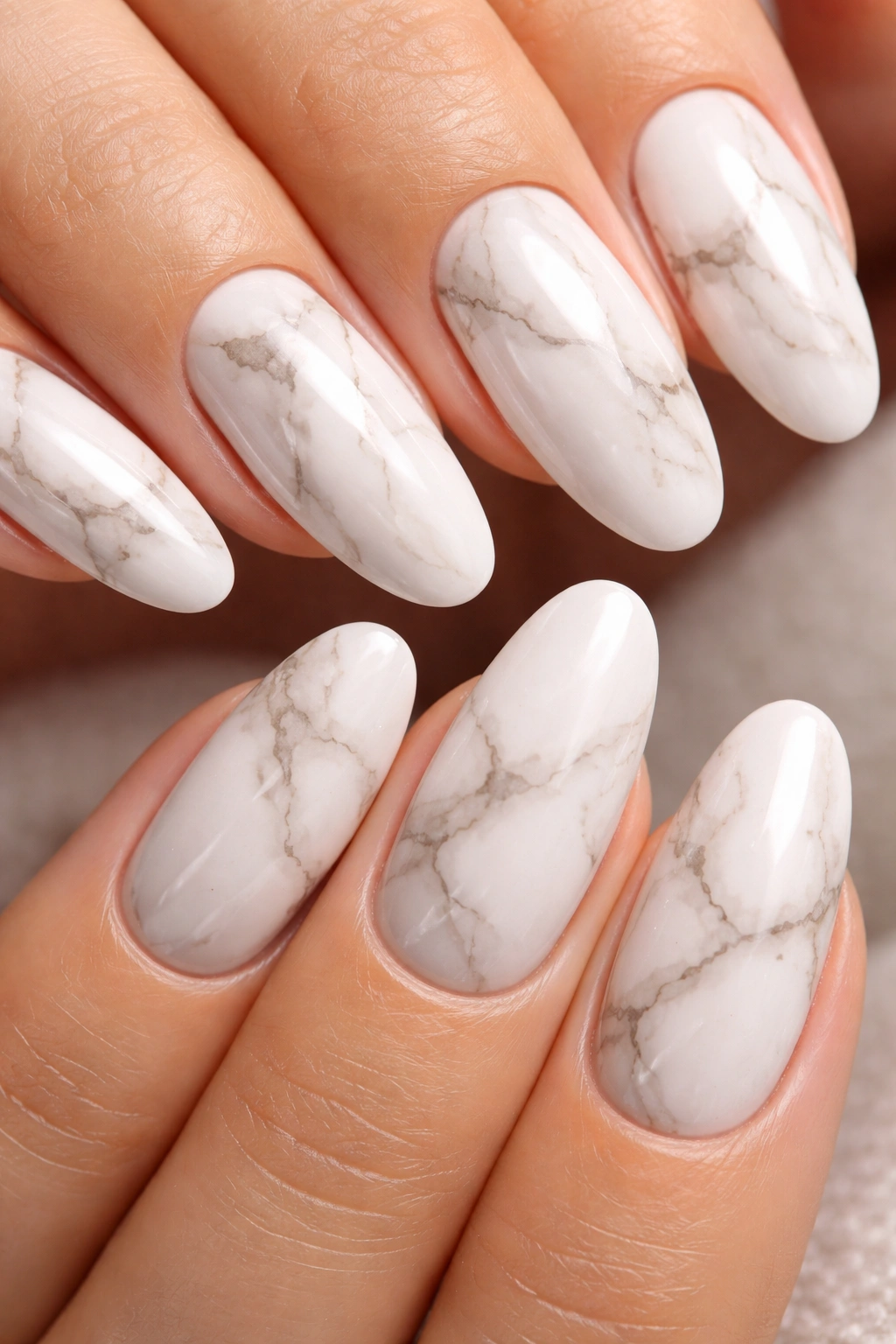 Close-up of white long oval nails with soft gray and taupe marble veining