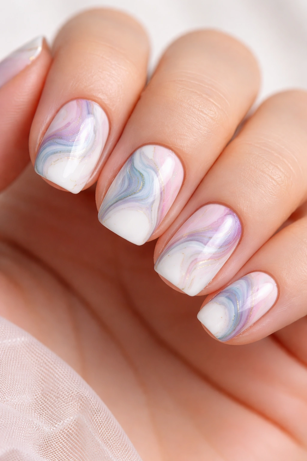 Close-up of white nails with colorful marble swirls on short squoval nails