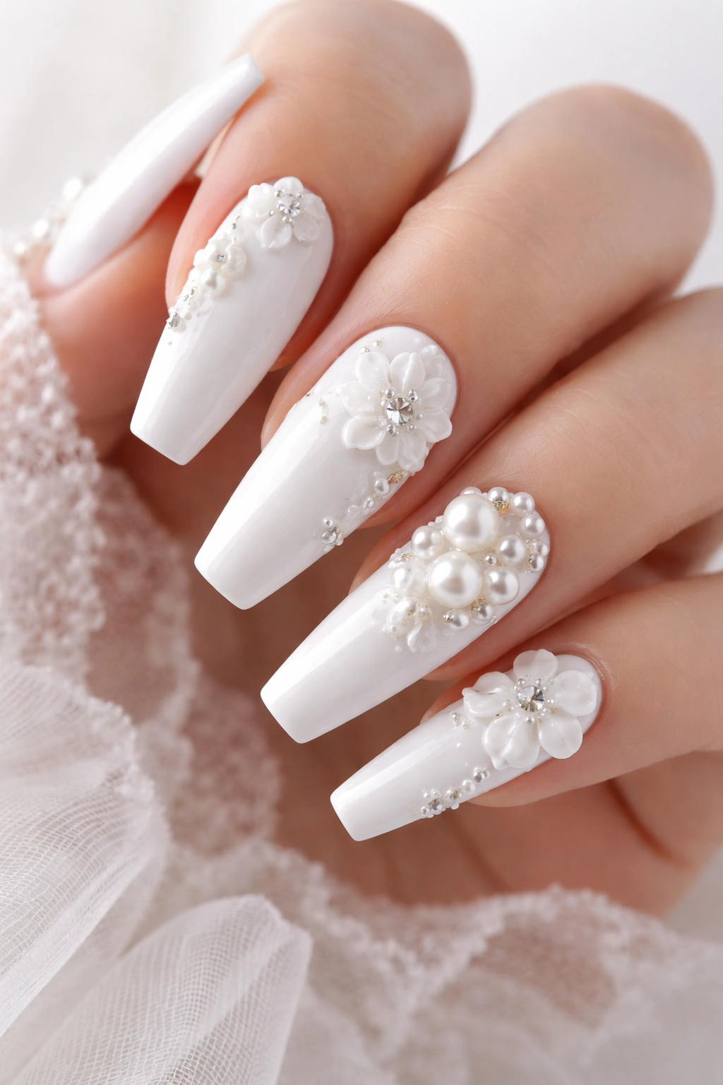 White nails with 3D pearls and flowers in a close-up.