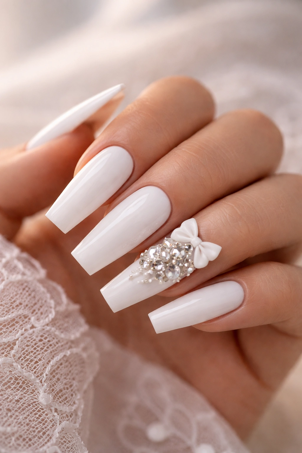 Close-up of white coffin nails with 3D bows and rhinestones on an accent nail