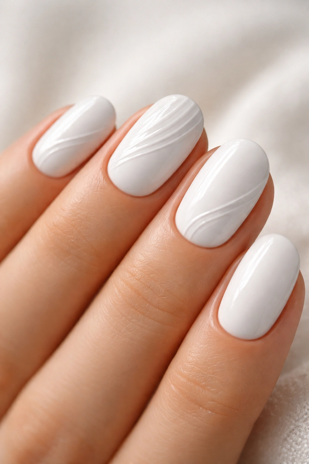 Close-up of white short oval nails with subtle 3D texture