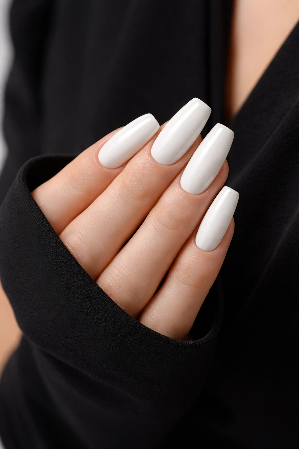 Close-up of white nails against a black dress sleeve