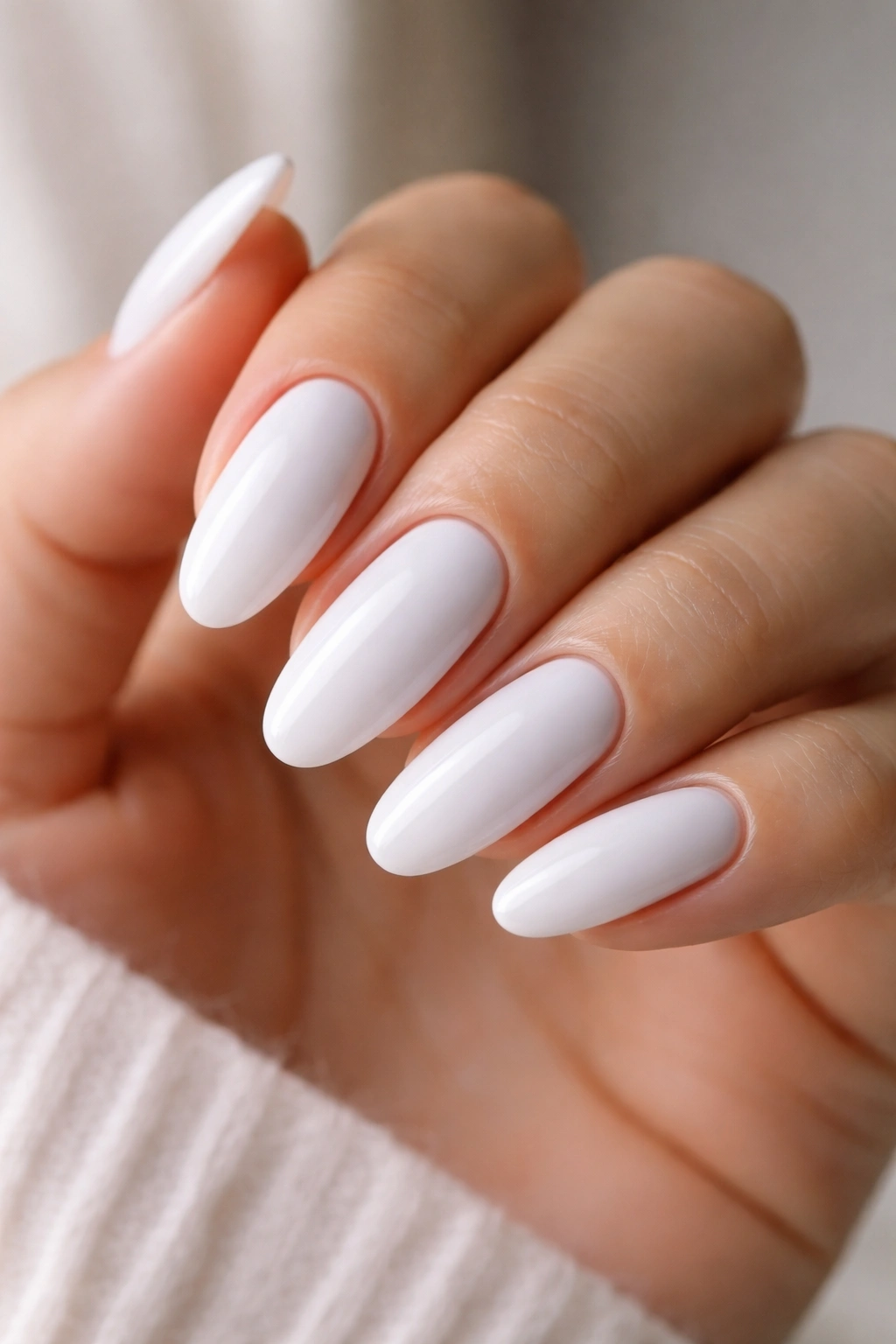 Close-up of pristine white long oval nails with glossy finish