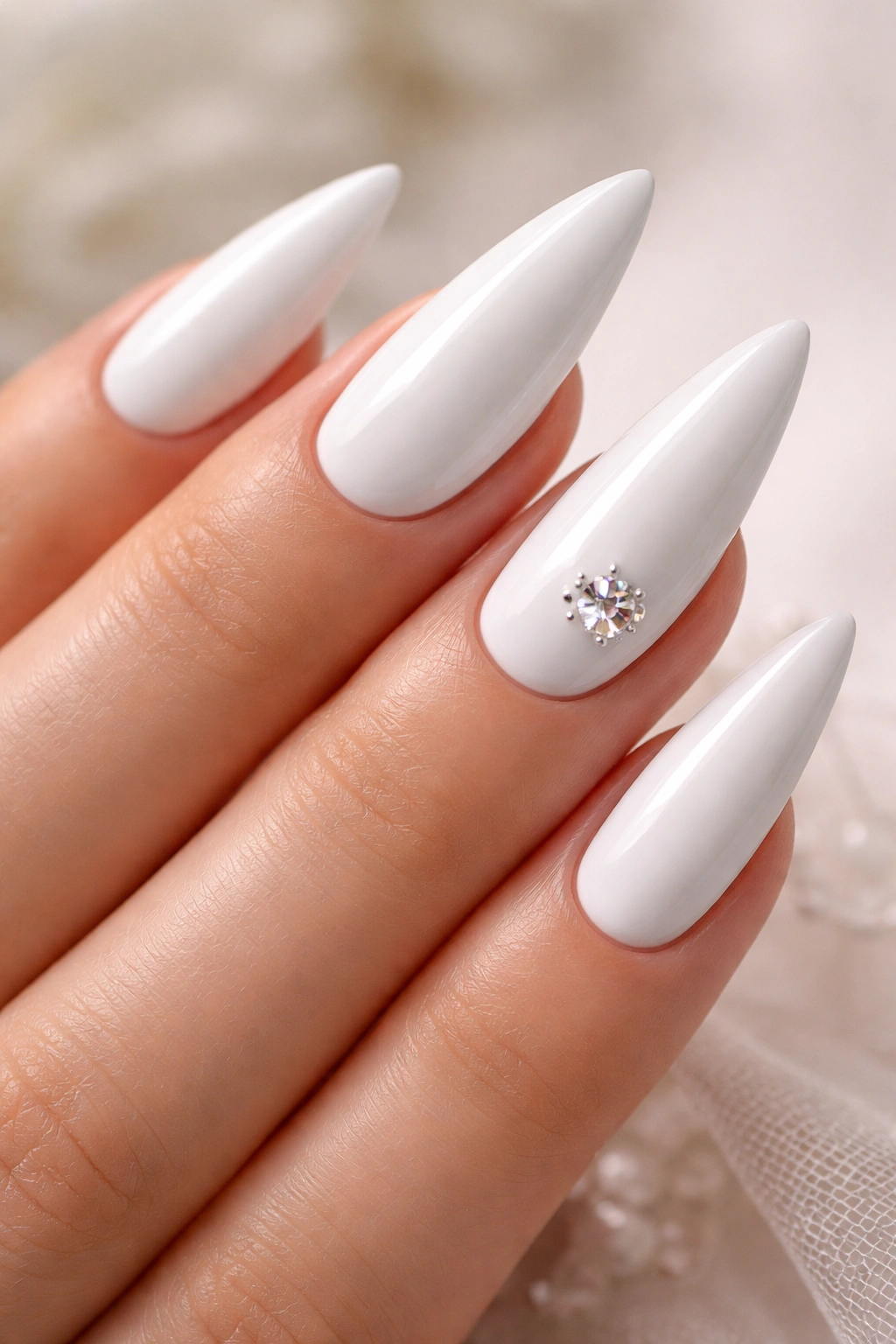Close-up of elegant white stiletto nails with a single diamond accent on the ring finger