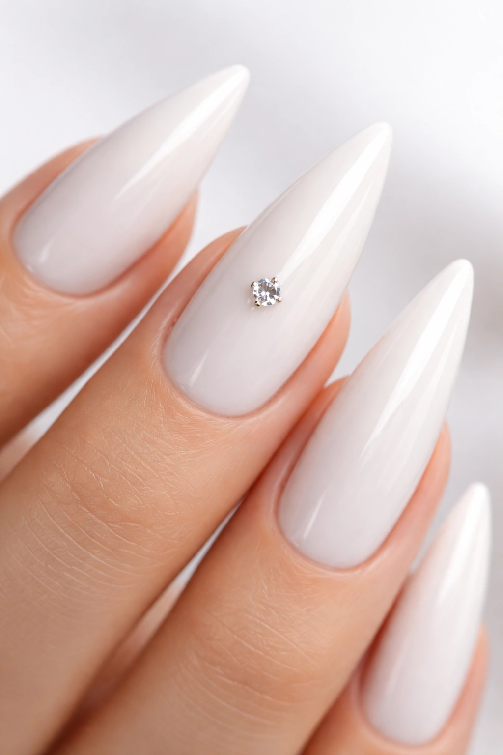 Close-up of a stiletto nail with white base and a single centered rhinestone