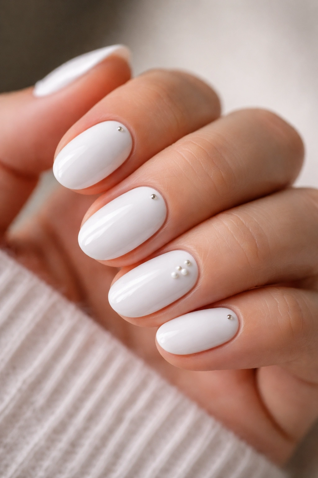 Close-up of white oval nails with tiny dot details