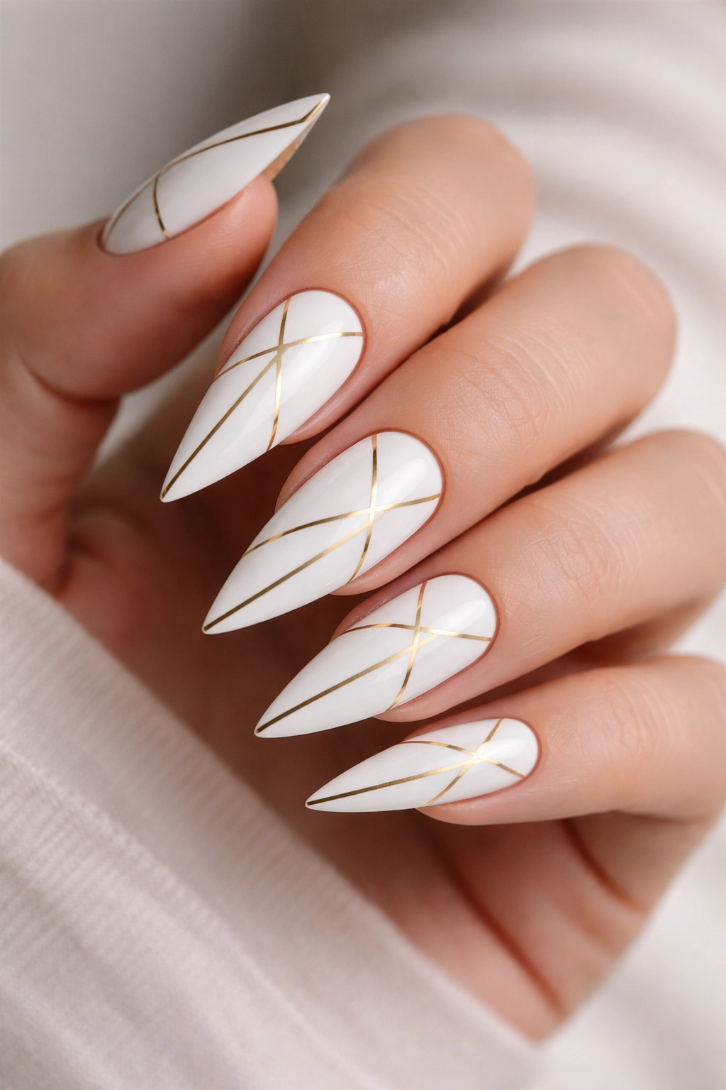 White stiletto nails with thin gold geometric lines