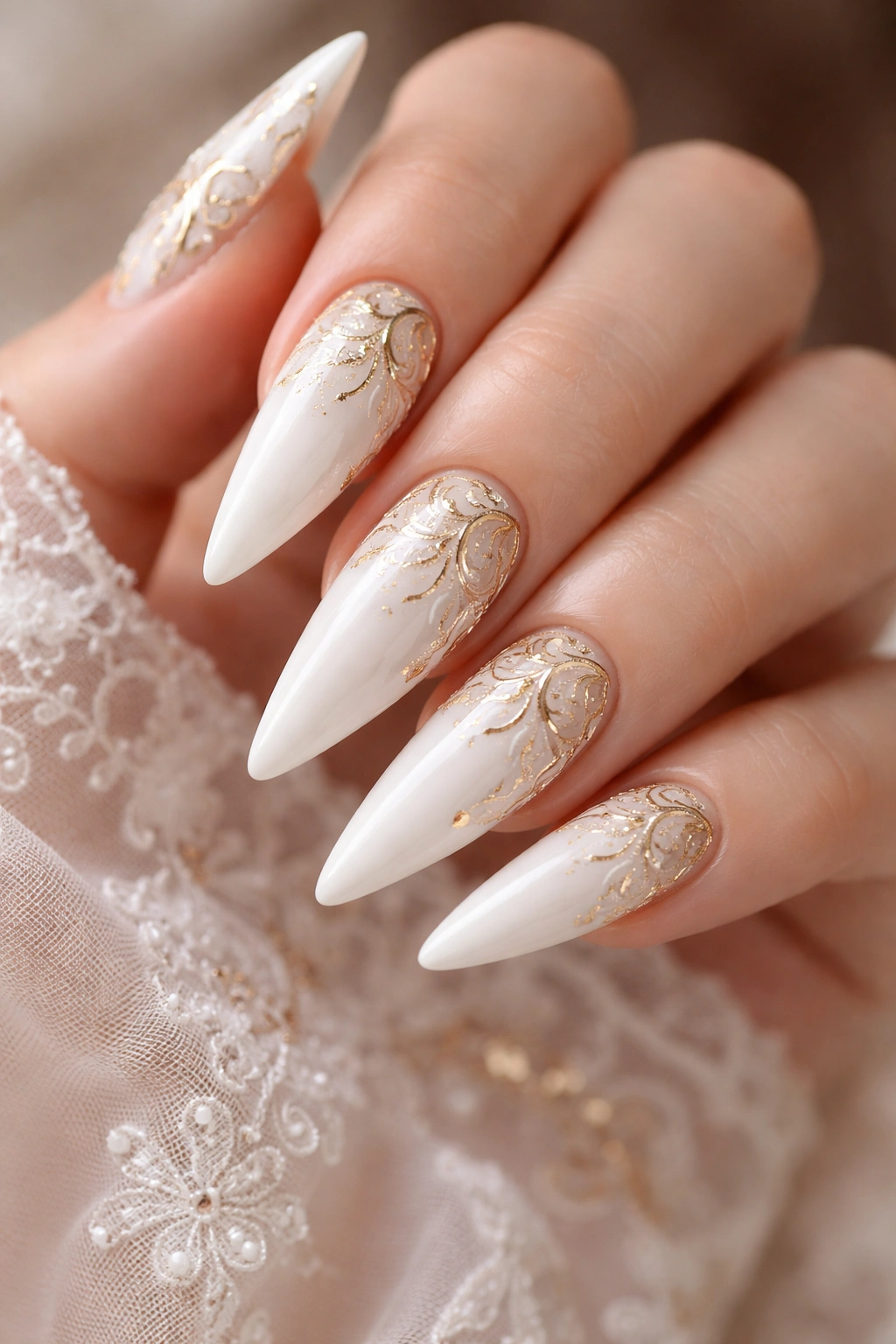 White stiletto nails with intricate gold filigree on a clean background