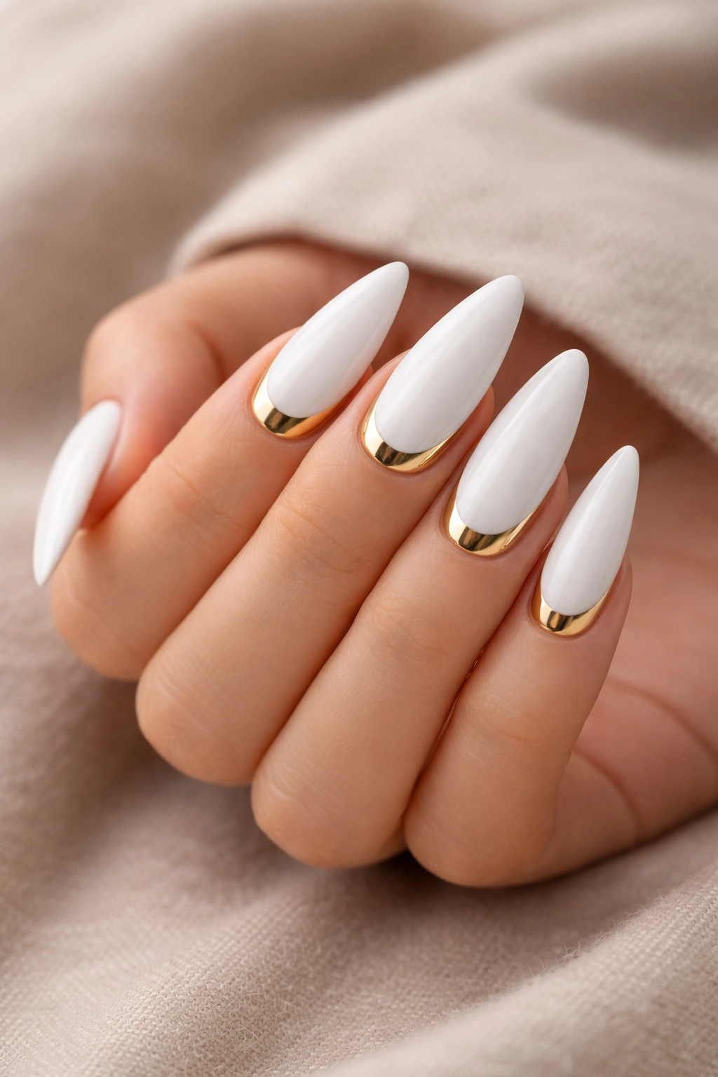 White stiletto nails with gold half-moon accents at the base