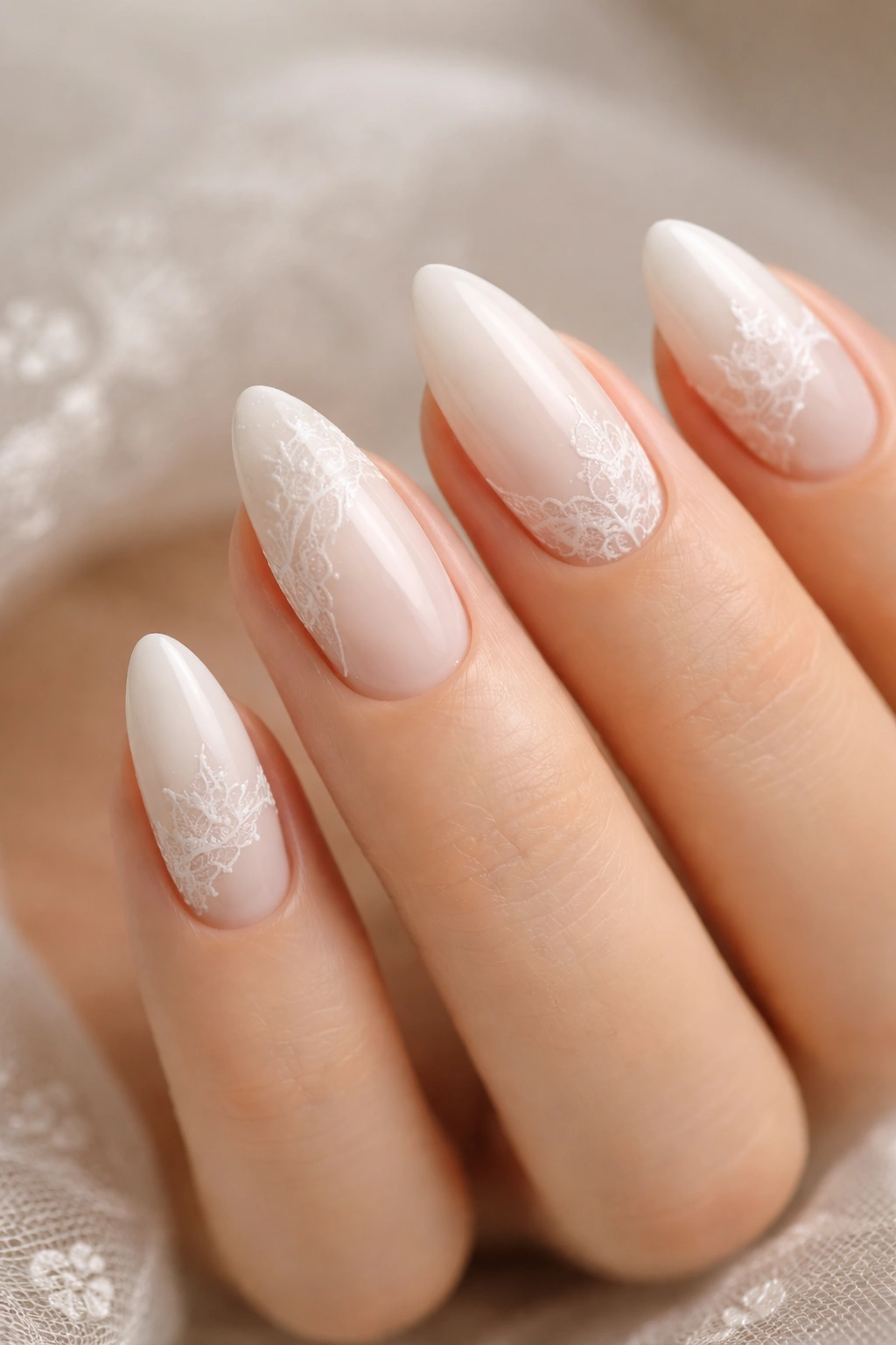 Close-up of white almond nails with lace-inspired details