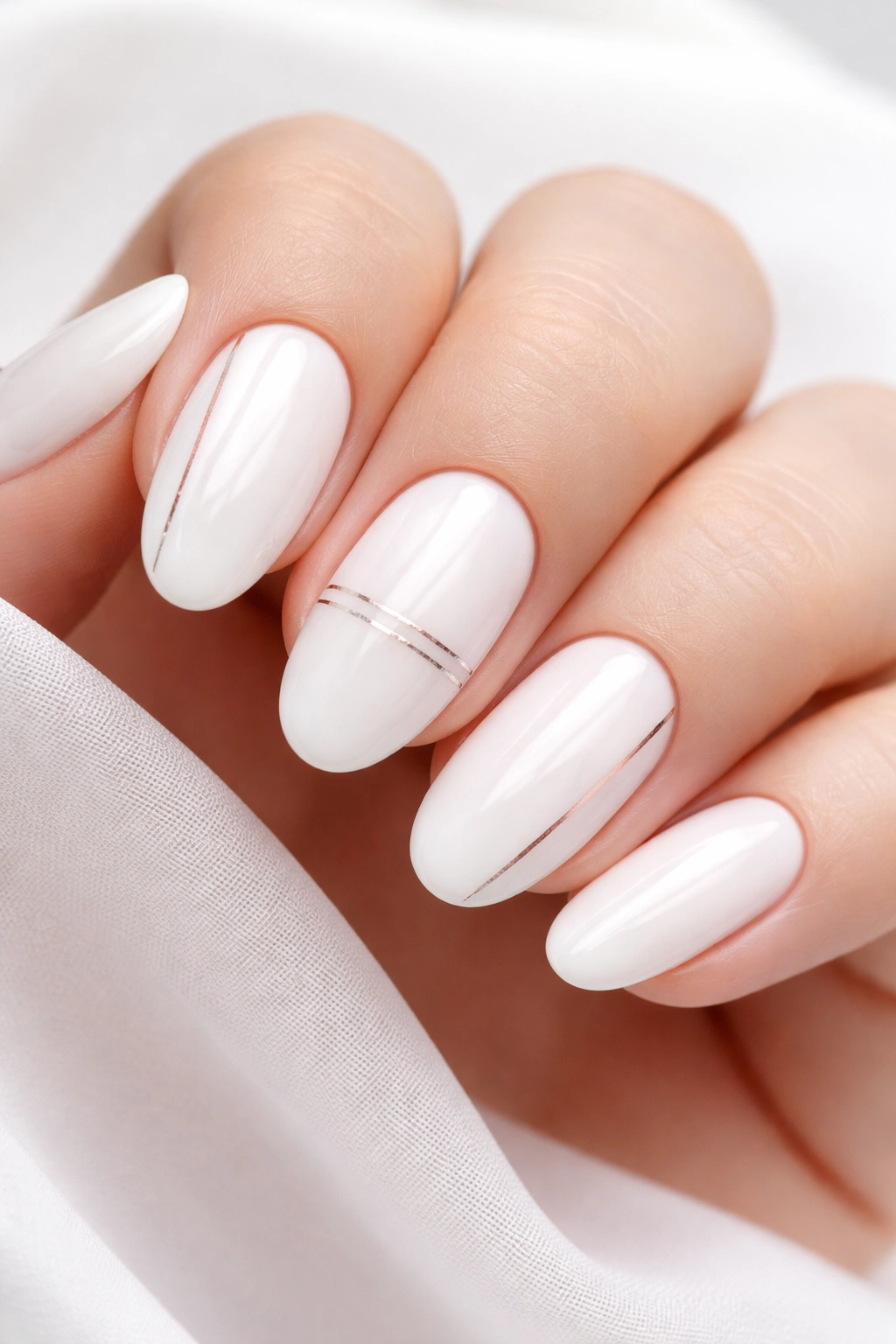 Oval nails with white base and thin metallic lines