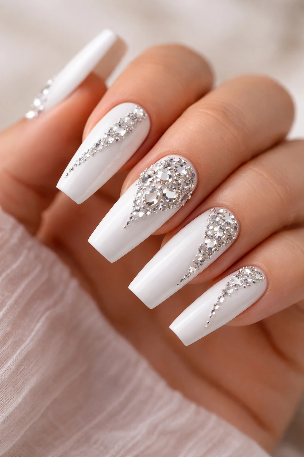 Close-up of white-base coffin nails with 3D rhinestones arranged in a design