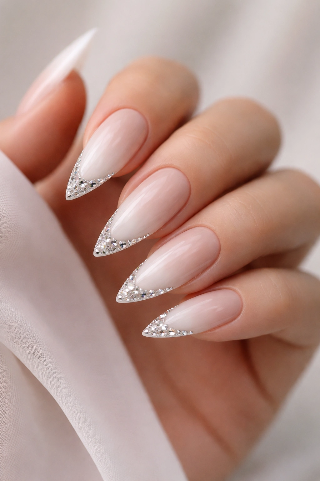 Close-up of white French ombre stiletto nails with rhinestone tips
