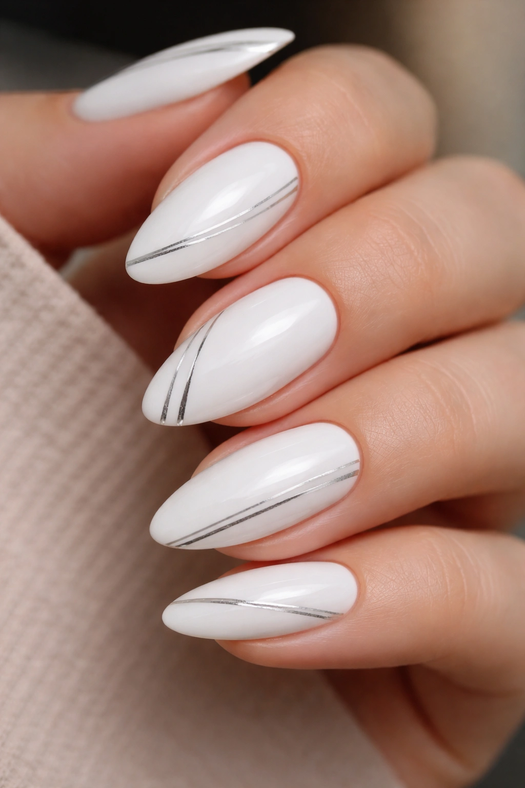 Close-up of white almond nails with thin silver lines
