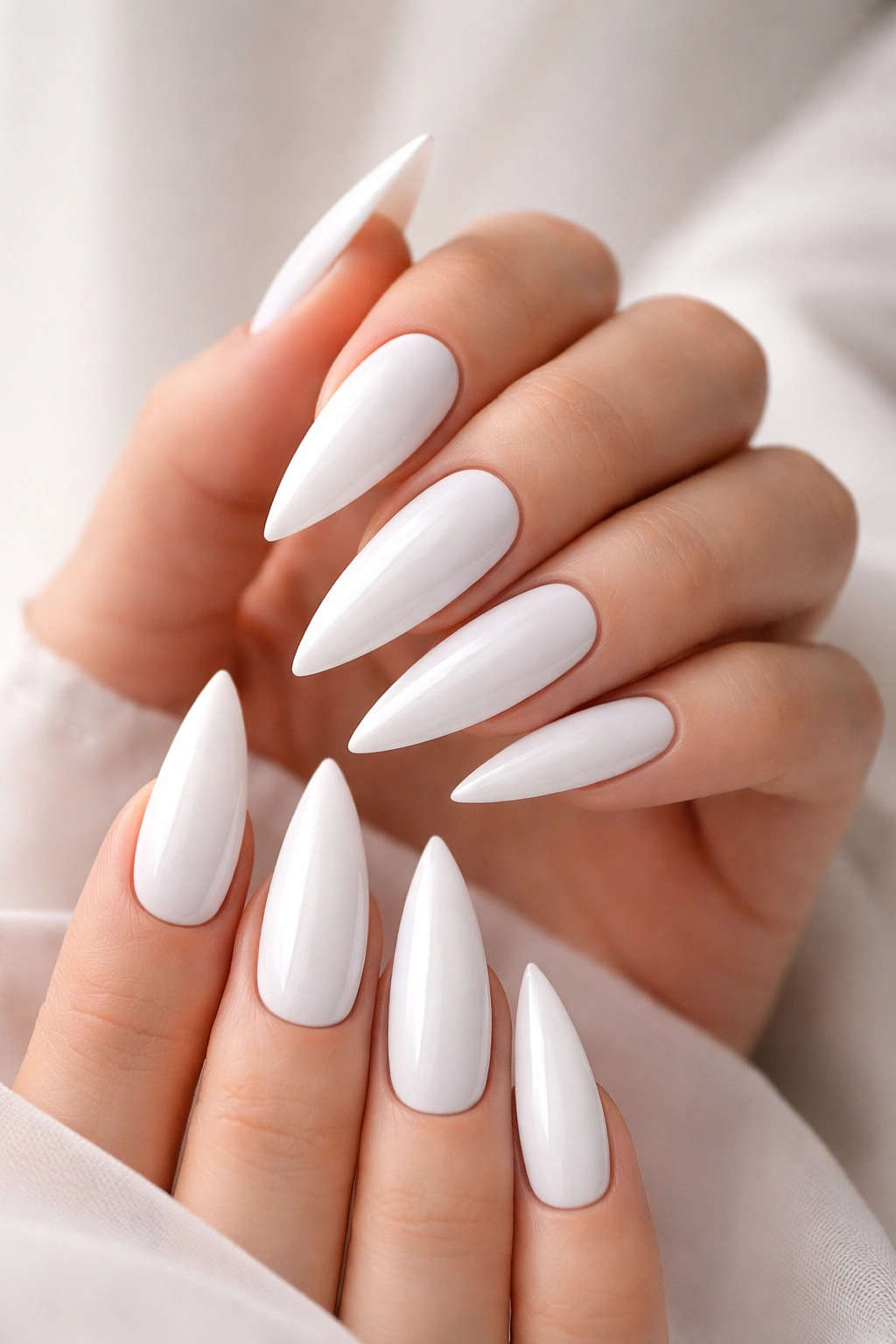 Close-up of pure white glossy stiletto nails with razor-sharp edges on hands