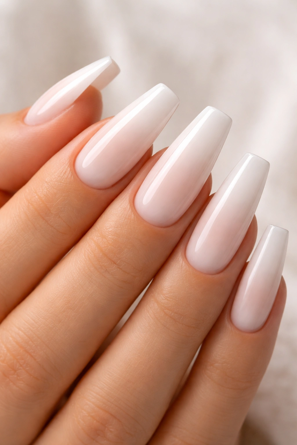 Close-up of white coffin nails with an ombre gradient from base to tip