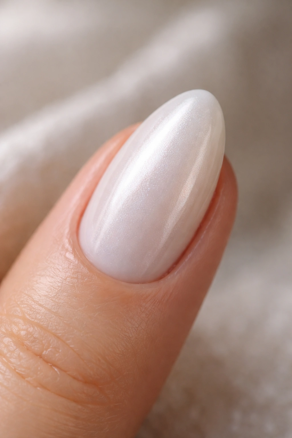 Close-up of a white pearl nail with glossy iridescent finish