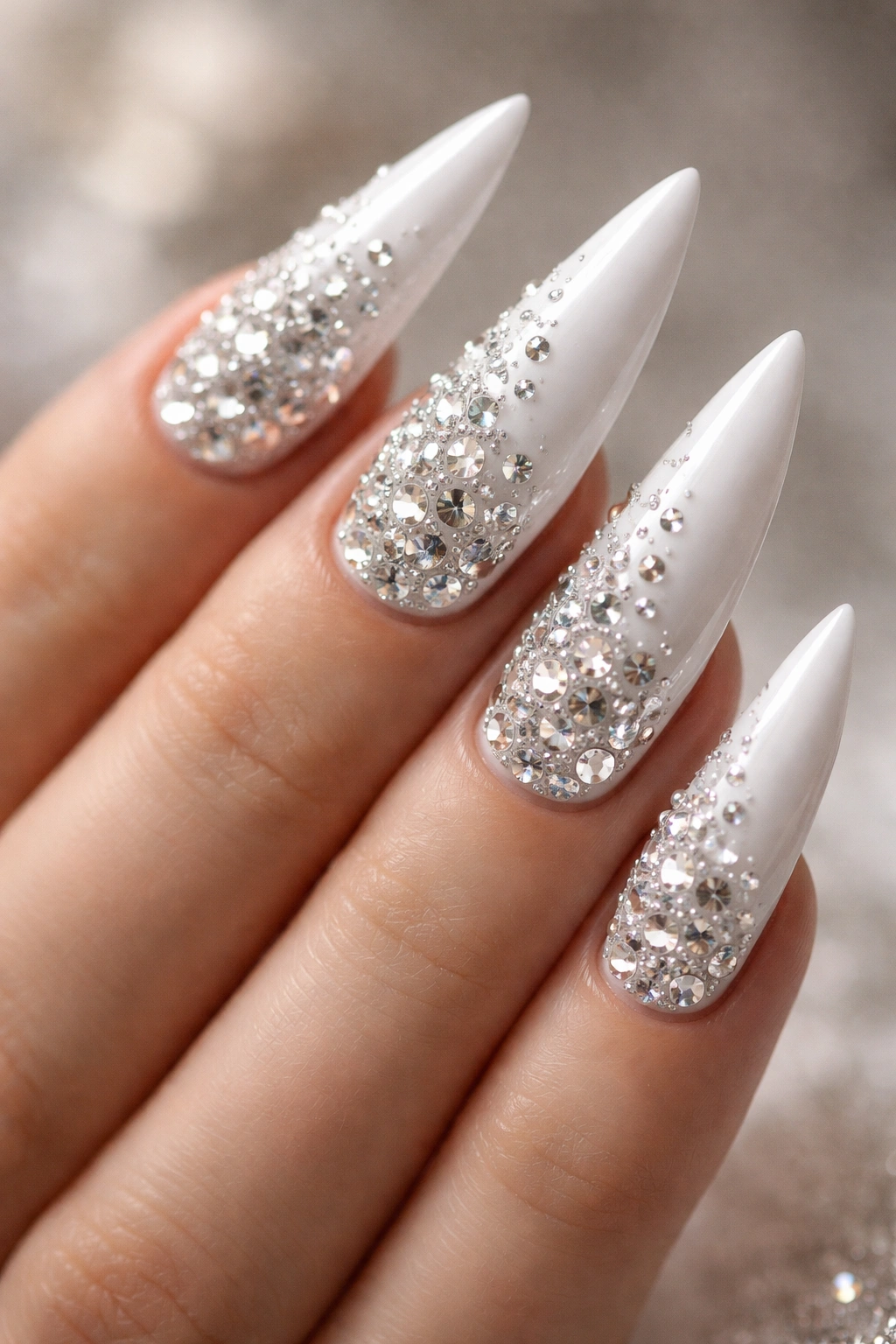 Close-up of white stiletto nails with rhinestones scattered for sparkle
