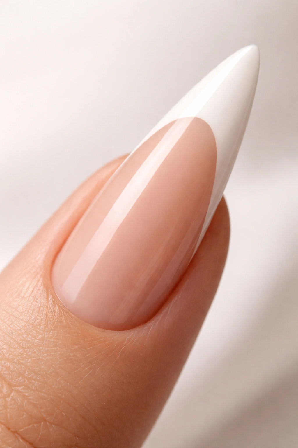 Close-up of white-tipped stiletto nail on nude base with precise line work