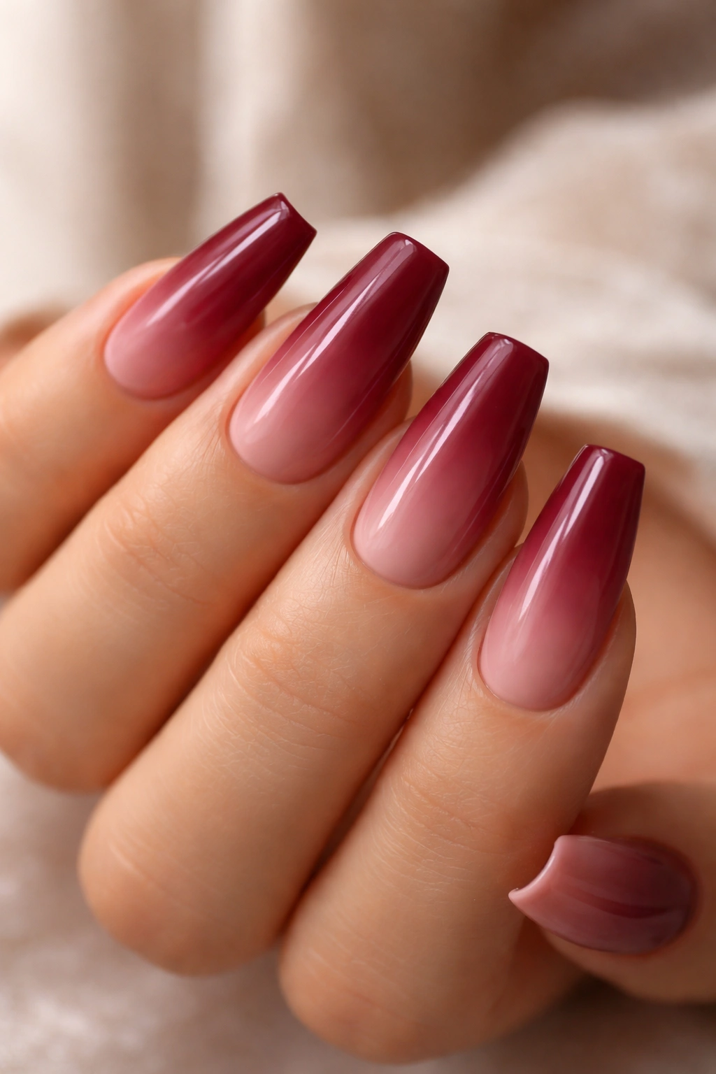 Close-up of wine red to dusty rose ombre nails on medium coffin shape