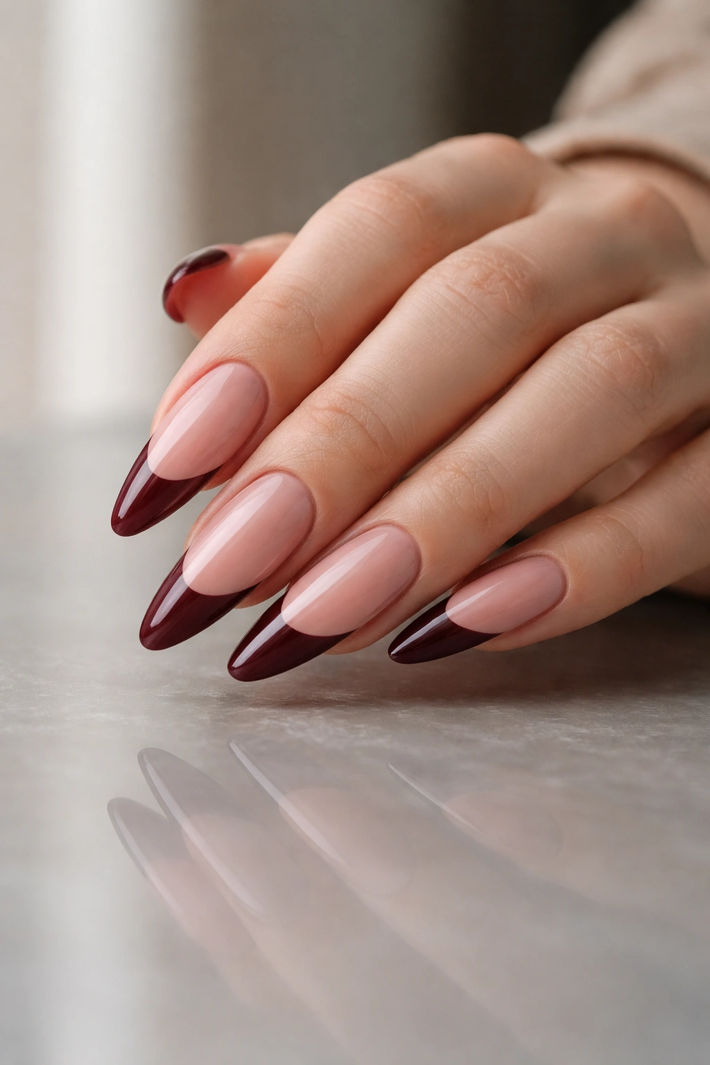 Almond nails with deep wine red tips on a glossy nude base