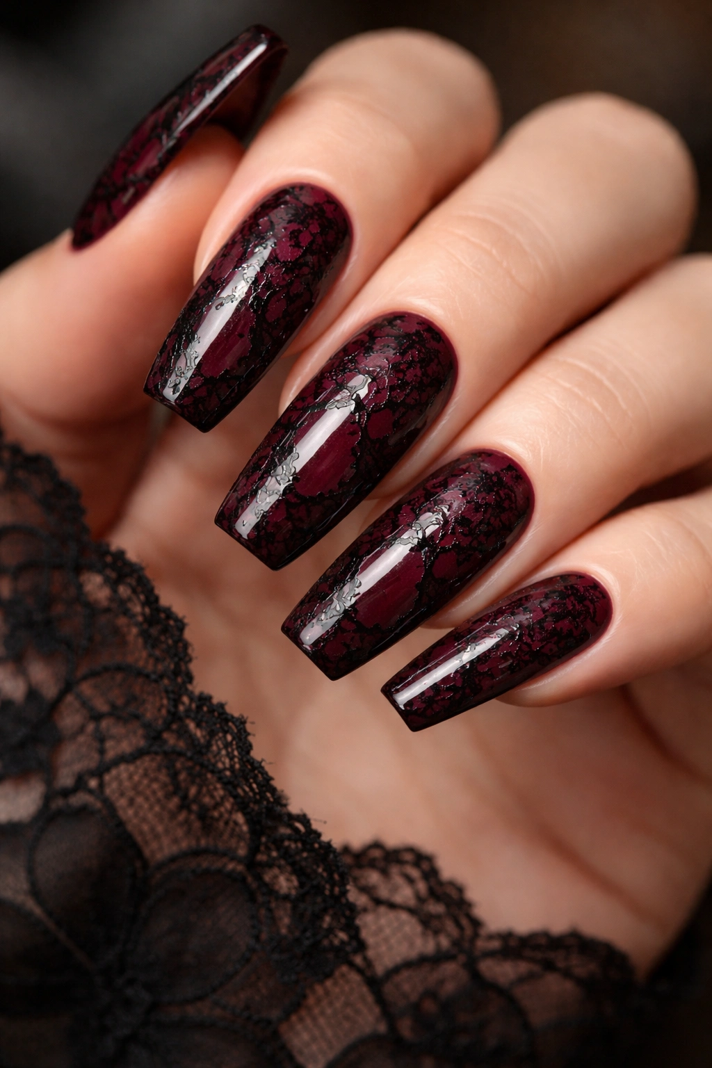 Close-up of wine red coffin nails with black lace overlay