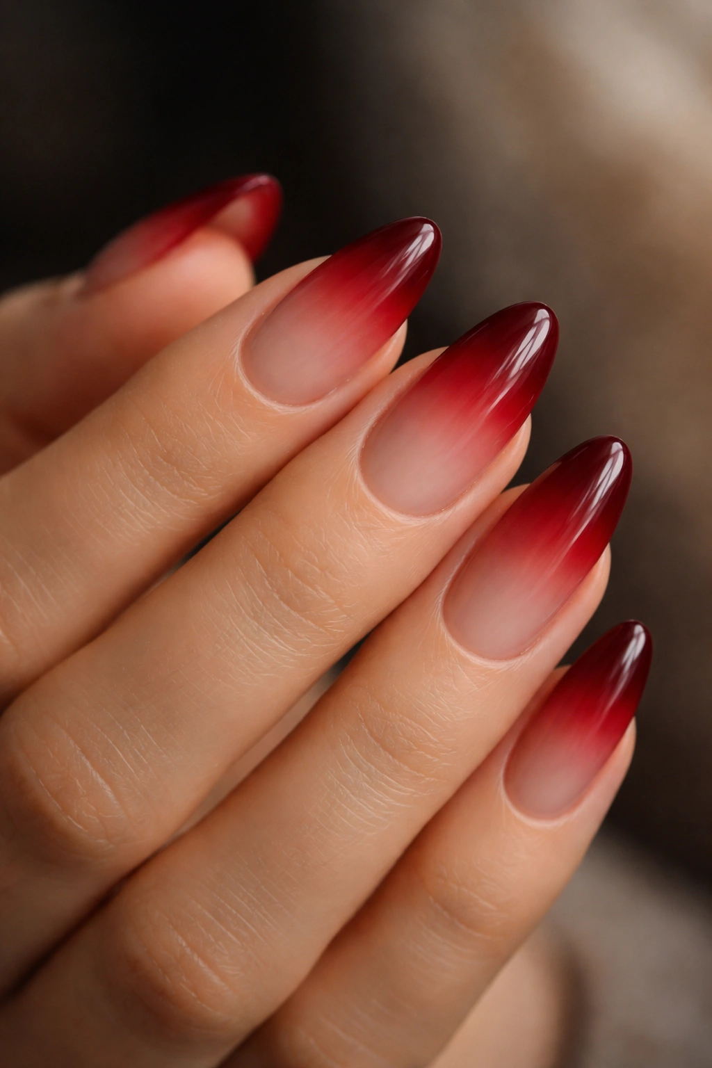 Almond nails with wine red ombre over nude base on a hand
