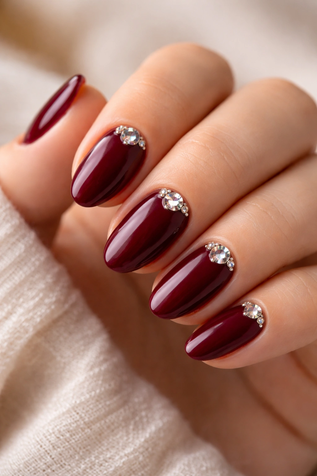 Wine red nails with rhinestone cluster near cuticle