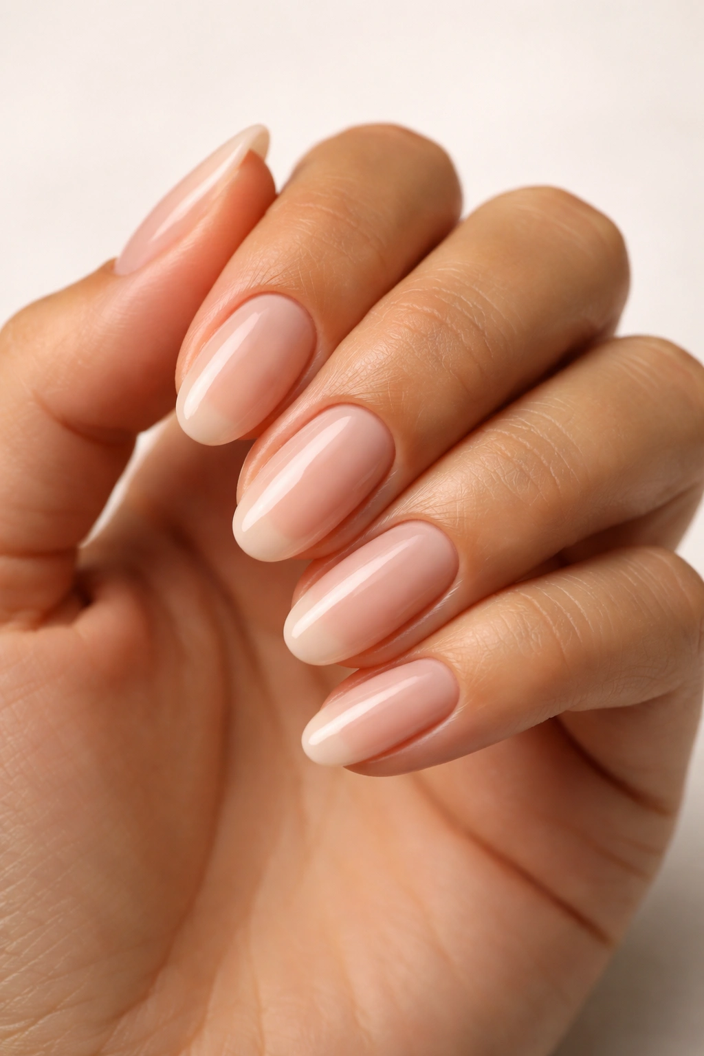 Close-up of an olive-skinned hand with a finished manicure in a neutral shade.