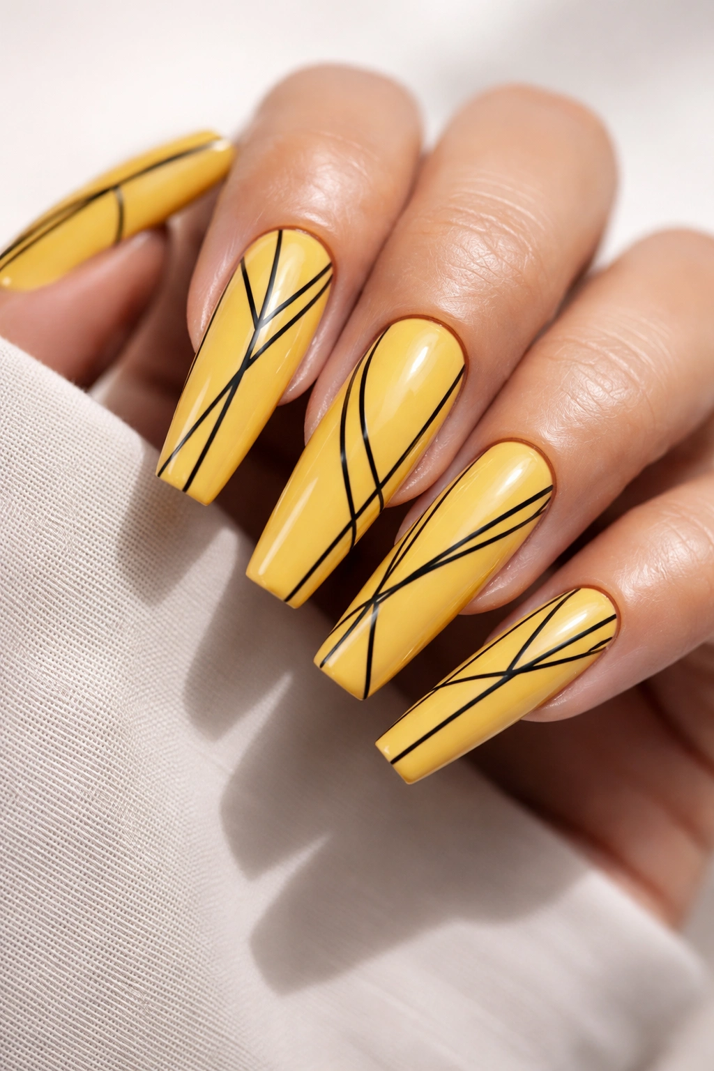 Close-up of yellow coffin nails with black geometric line art.