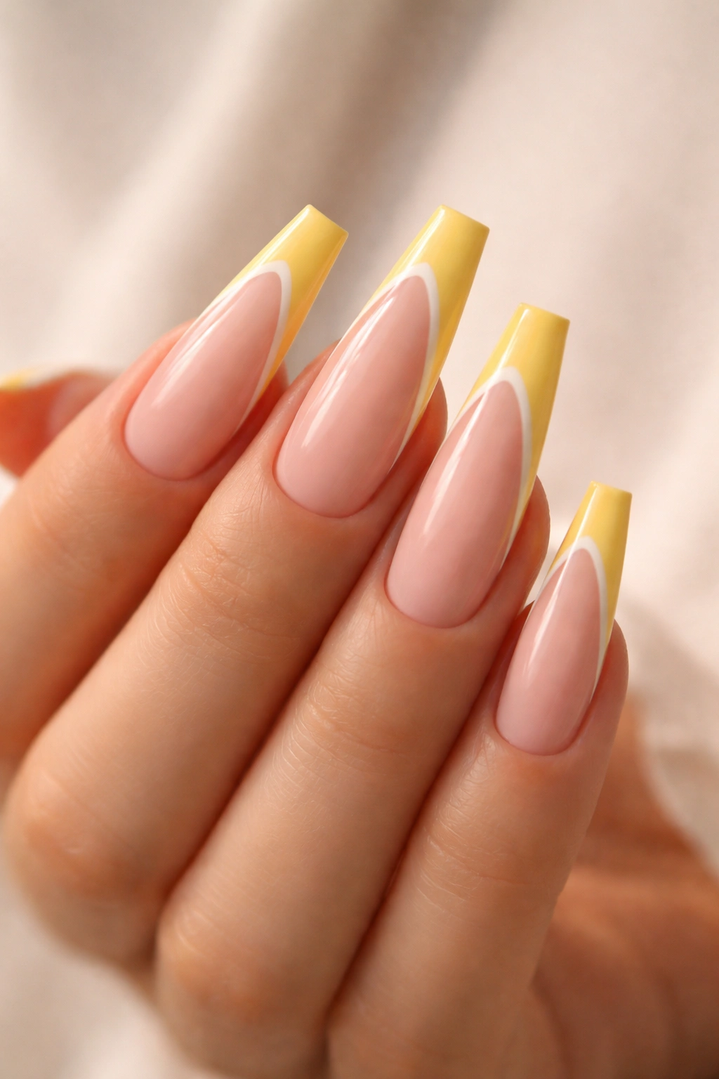 Close-up of long coffin nails with yellow base and extended white French tips.